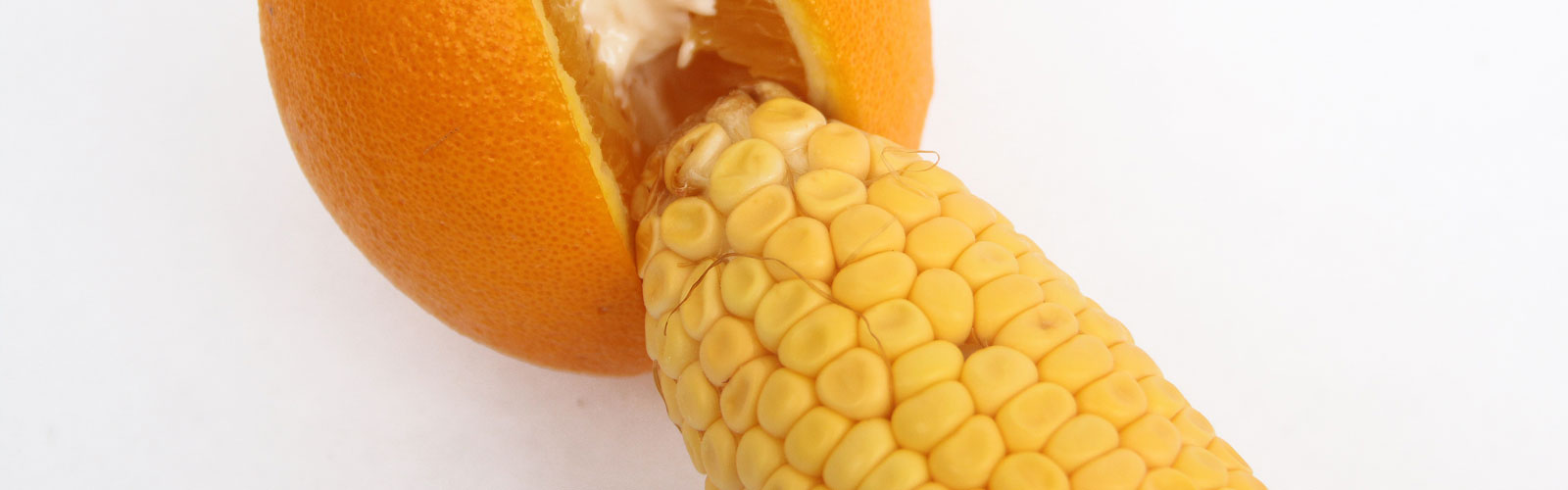 Cob of corn next to orange sliced open