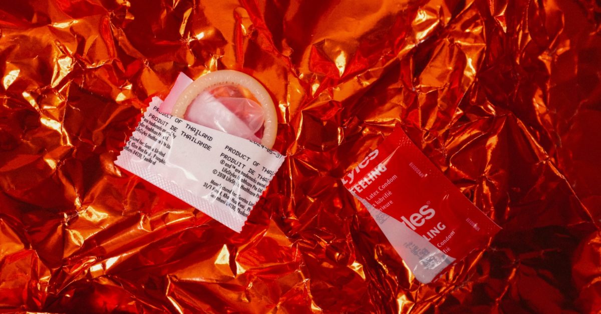 Open condom and wrapper metallic background
