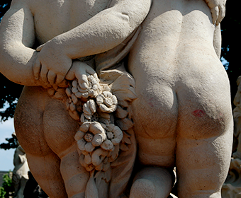Butt shot of two stone cherubs holding hands behind themselves