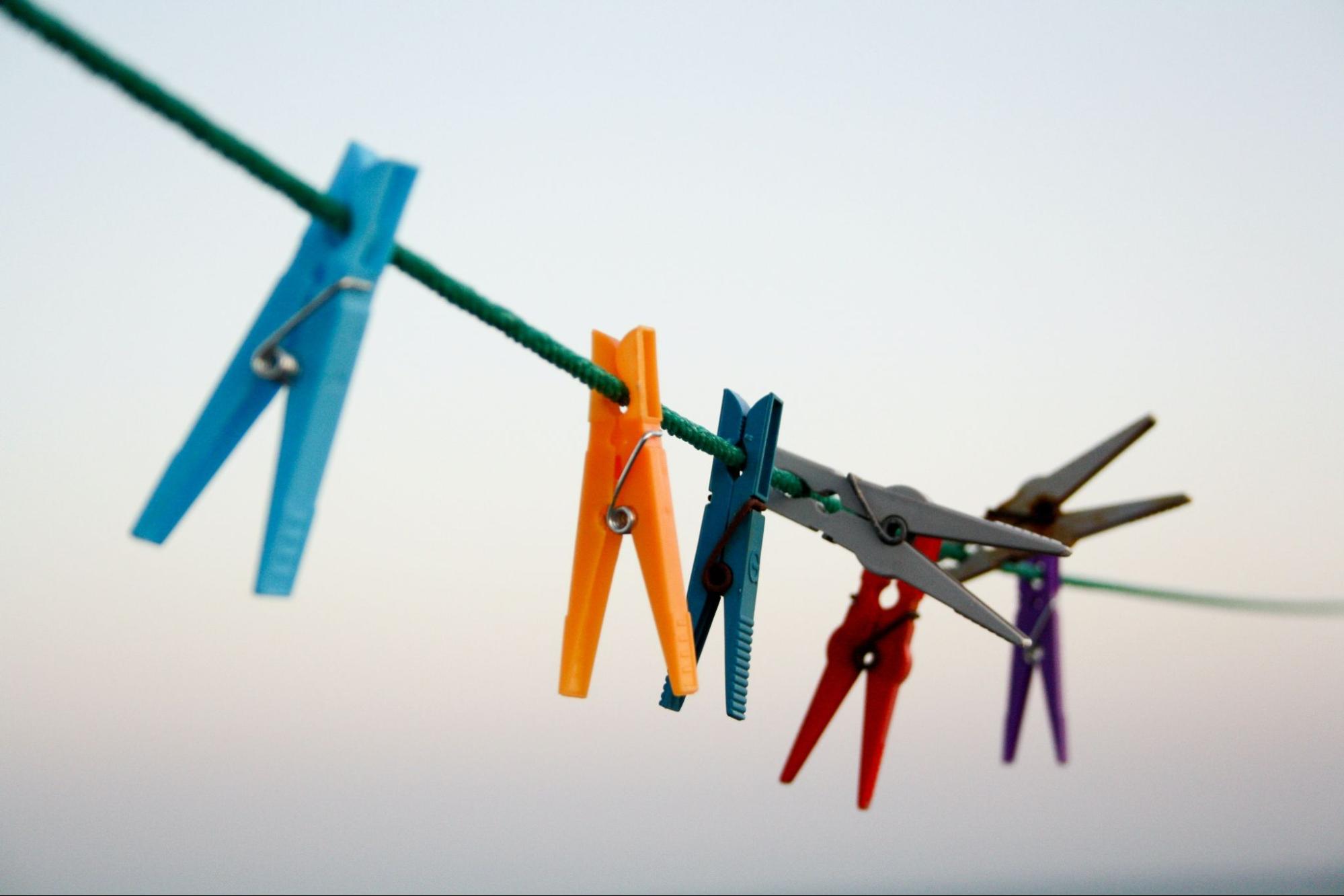 7 different coloured pegs hanging from a line