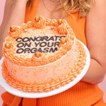 Abbie Chatfield holds a cake saying 'Congrats on your Orgasm' as part of her promotion for her Vush Vibrator