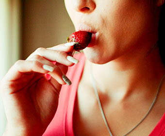 A woman takes a sensual bite out of strawberry. Some fruits are said to be an aphrodisiac, and food play as foreplay may be a way to upgrade your sex life.