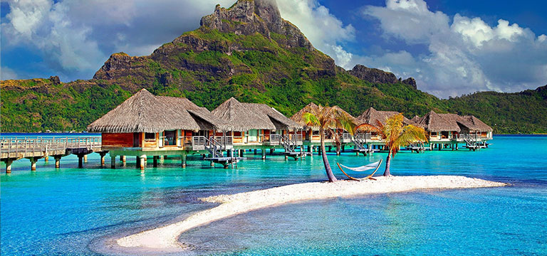 Huts sit over the clear blue waters of the Pacific in Bora Bora