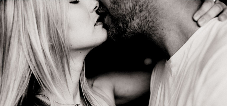 A woman and man kiss sensually