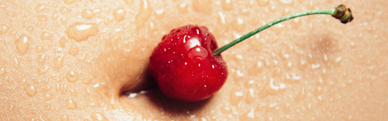 A bright red cherry sits in a person