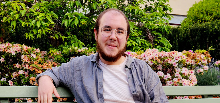 Intimacy coordinator Micah sitting outside on a park bench